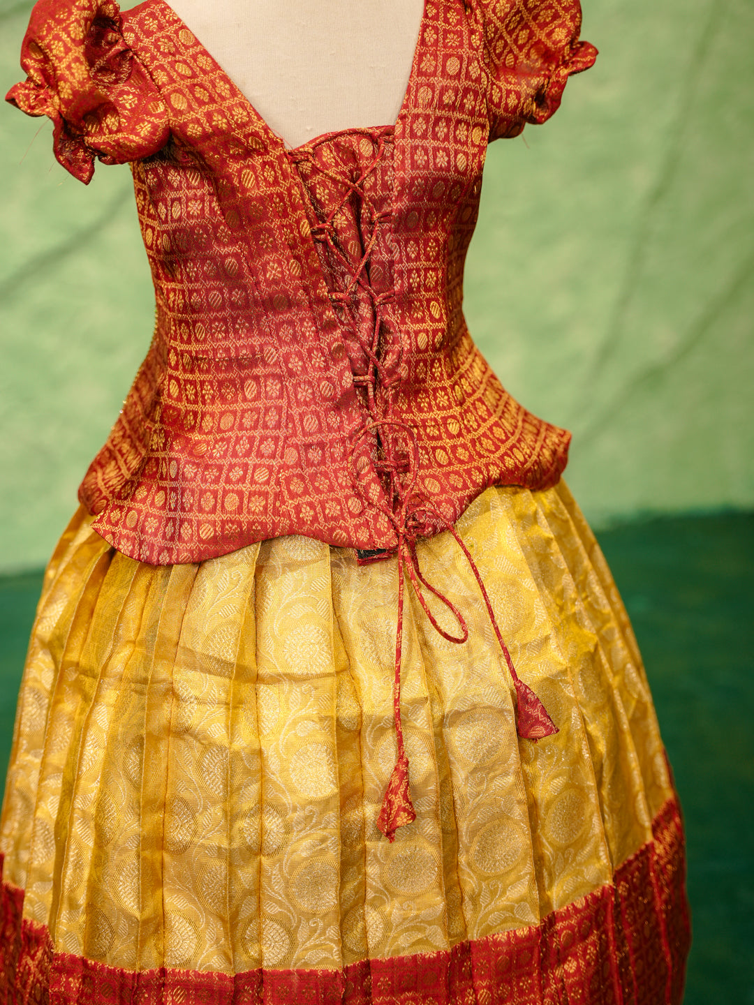 Red and yellow pattu pavadai in pure Kanchipuram silk with zari checks and puff sleeves — back view